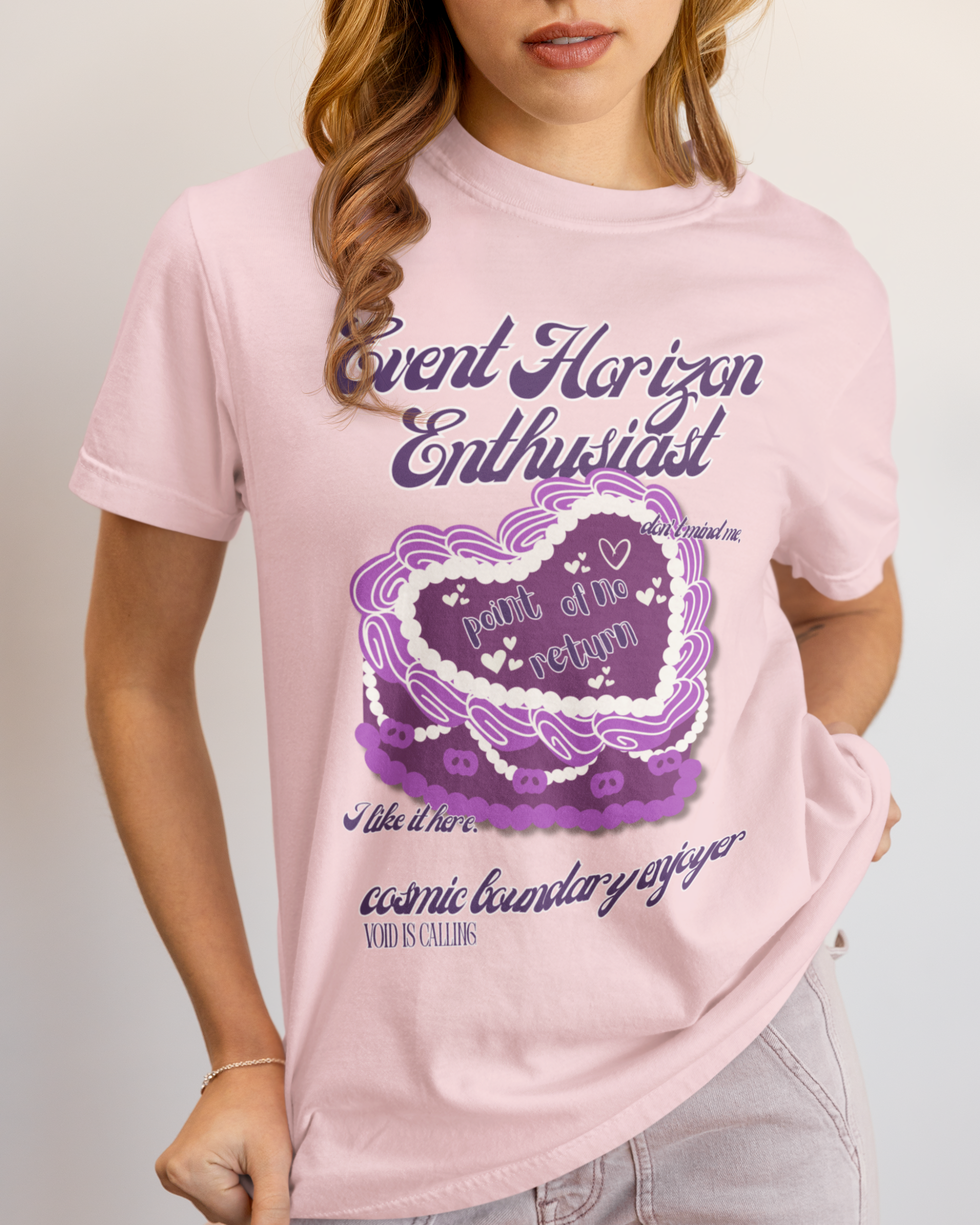 Person wearing a pink t-shirt with purple graphic design and text.